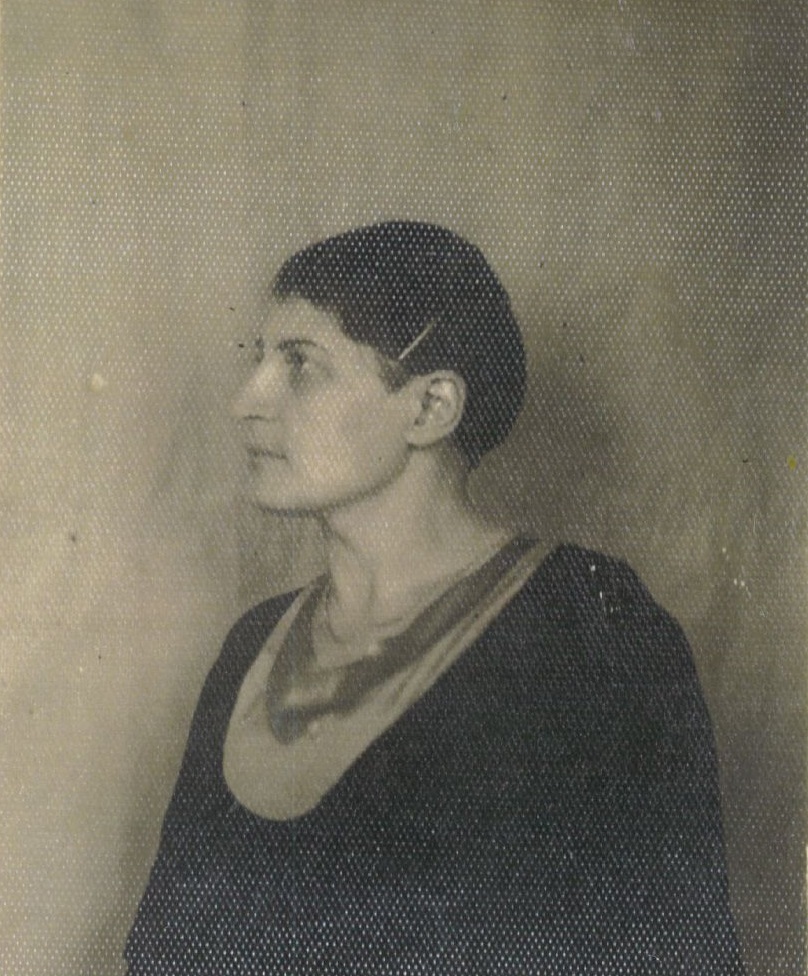 Czarno-biała fotografia portretowa przedstawiająca kobietę z krótkimi, ciemnymi włosami, ukazaną z profilu, na jednolitym tle